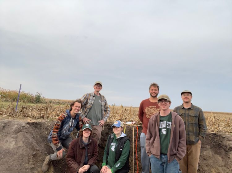 Dr. Barret Wessel with a group of students in the MSU Soil  Team in a field.