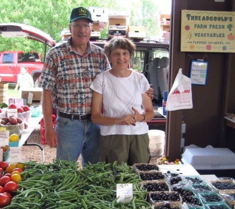 Earl and Suzanne Threadgould with a table of vegetables.