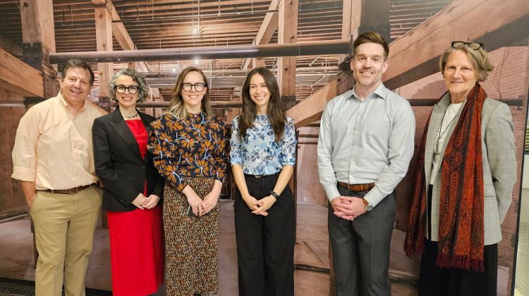 Climate Week NYC panelists posing for a picture in front of a background photo of a wood structure.