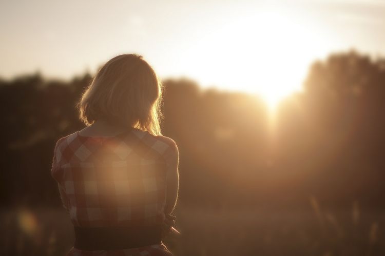 A woman standing outside during a sunset.