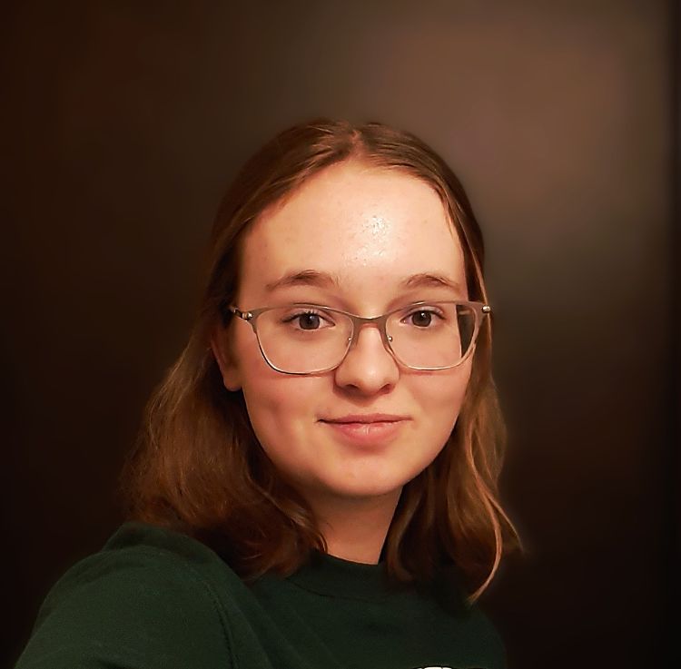A teenage girl with dirty blond hair and gold glasses.
