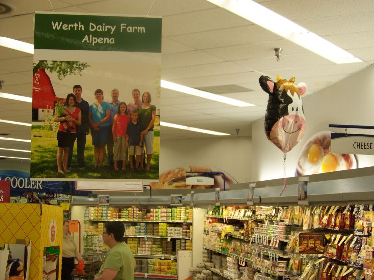 Werth Dairy Farm poster hanging in the dairy section of Neiman’s Family Market in Alpena. The photo used to create this poster was provided by the United Dairy Industry of Michigan (UDIM).