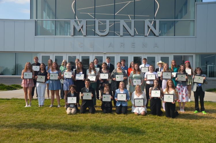 A group of youth standing outside and holding up their awards.