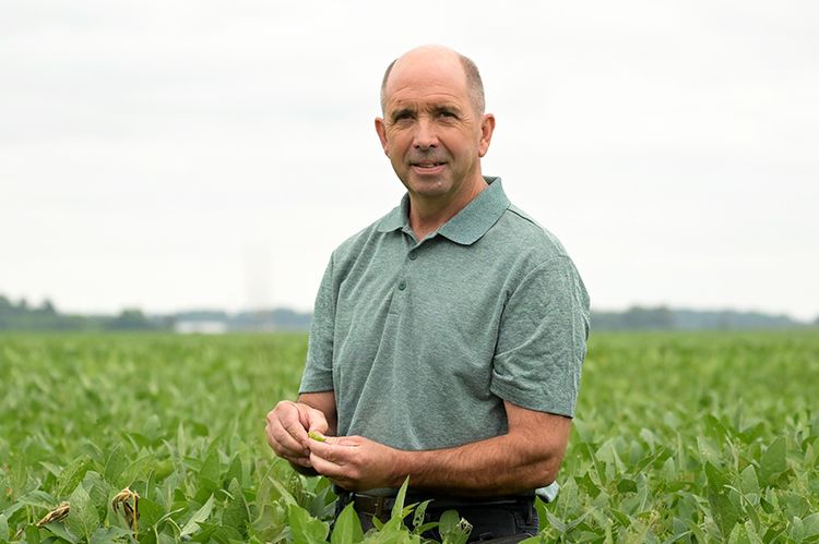 Neyer standing in a field of corn.