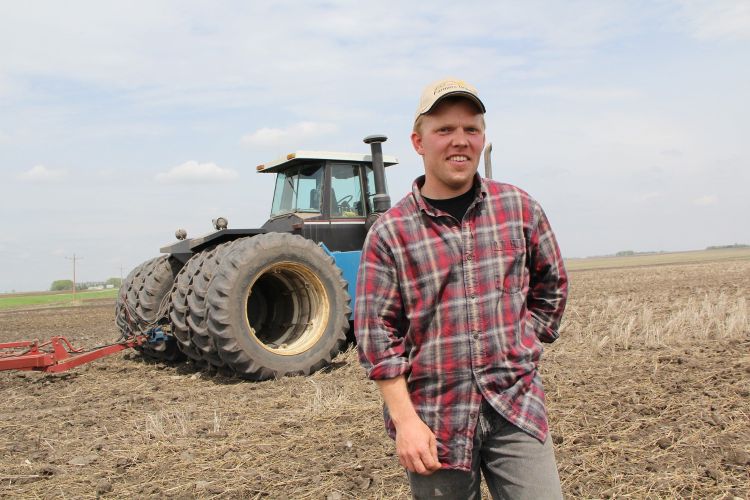 A man standing in front of his tractor.