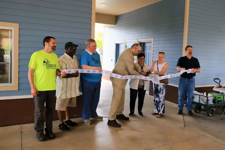 Seven people stand on a pavilion for a ribbon cutting ceremony at the downtown Escanaba Marketplace.