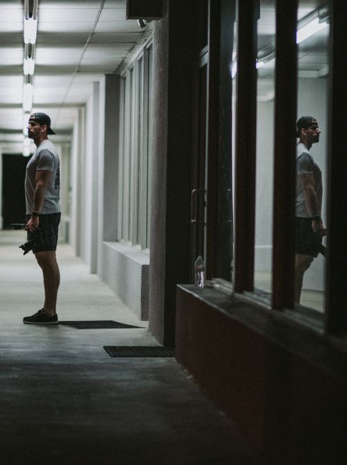 Solitary man standing outside a building and his reflection in the window.