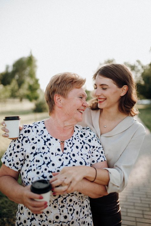 A young woman smiling and hugging an older woman.