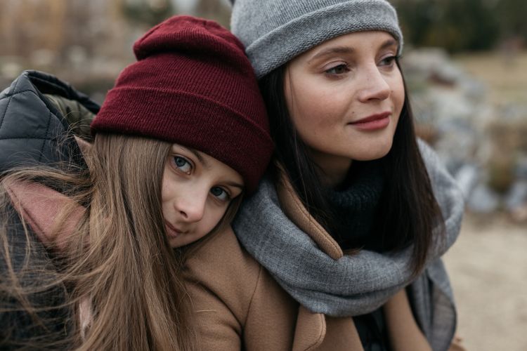 A younger woman rests her head on the shoulder of another younger woman.