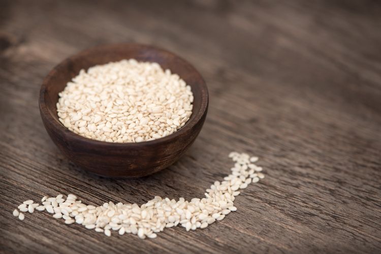 Small wooden bowl containing sesame seeds.