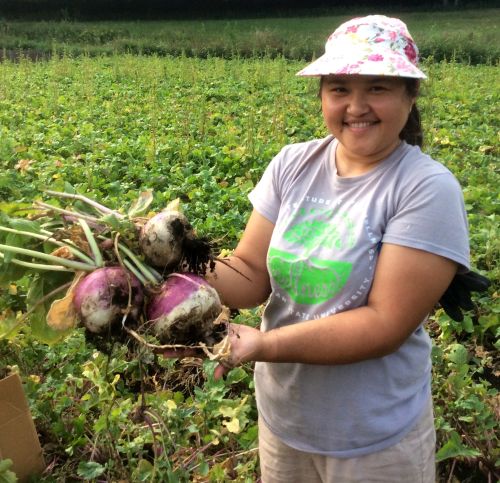 Saltanat Mambetova holding sugarbeets in a field.