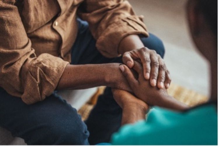 A photo of two people holding hands to support each other.