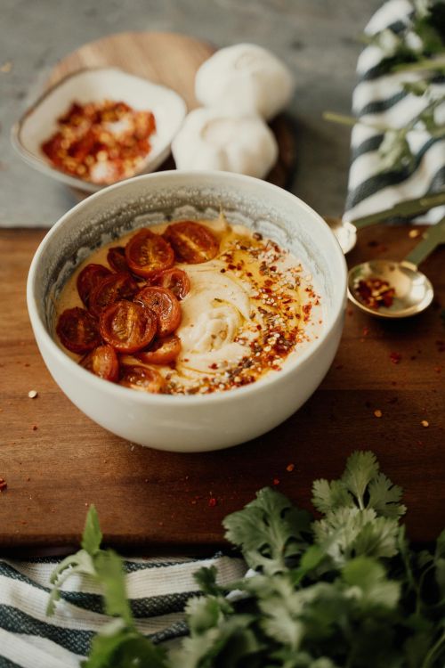 A bowl of hummus with tomatoes and sesame seeds.