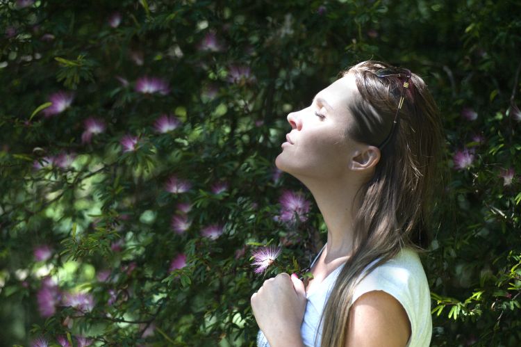 A woman closing her eyes and relaxing in nature.