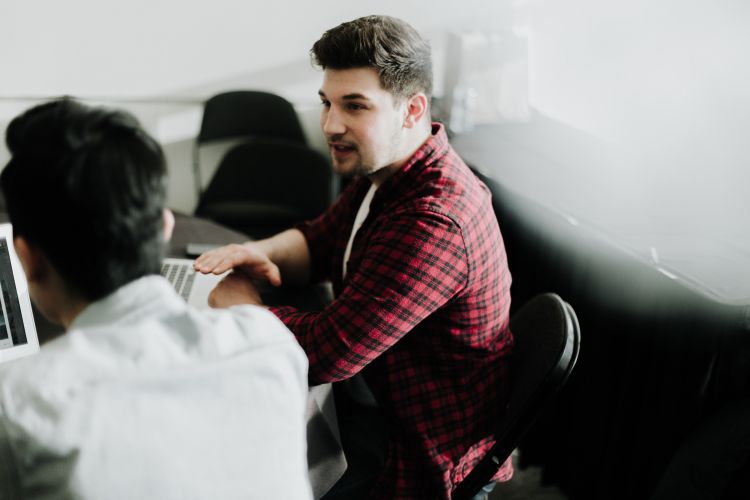 Man sitting at a computer talking to someone.