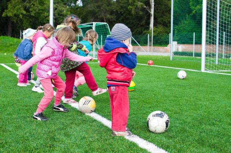 Kids lined up playing soccer in cold weather.