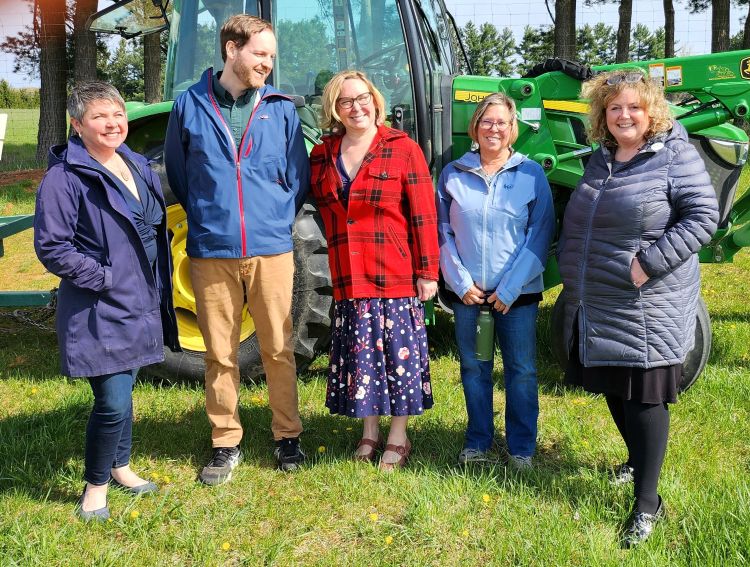 A photo of Remington Rice and others standing in front of a tractor.