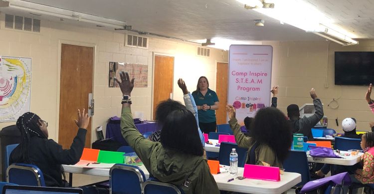 Participants raise their hands during a 4-H program.