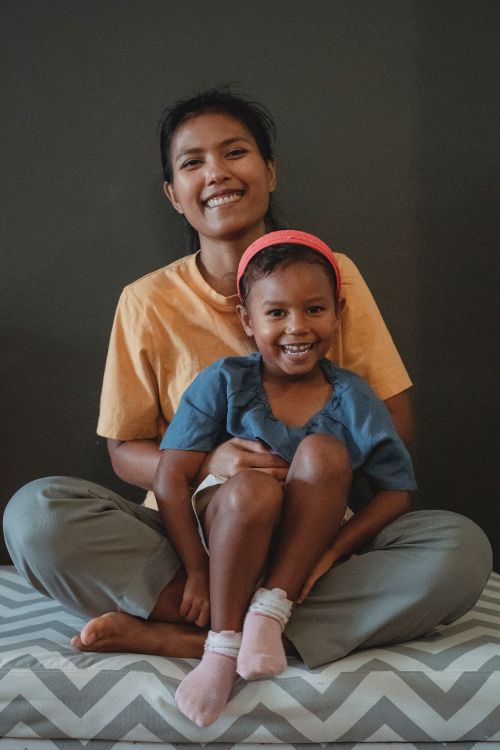 Woman and daughter sit together smiling