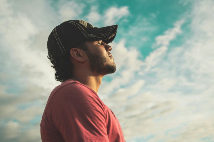 A man closing his eyes and practicing mindfulness outdoors.