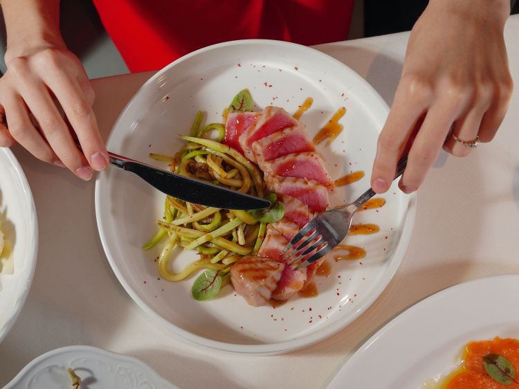 A person cutting up their food.