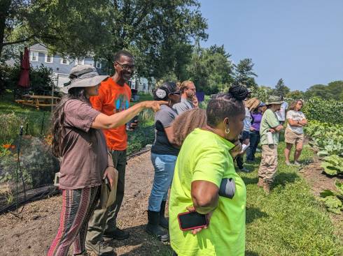 People gathered at a farm. One person is pointing toward the field.