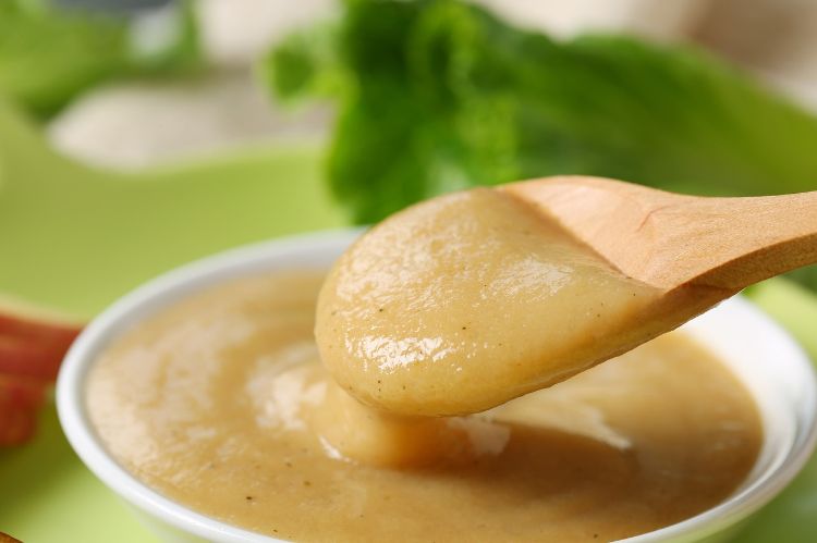 Applesauce being picked up with a spoon.