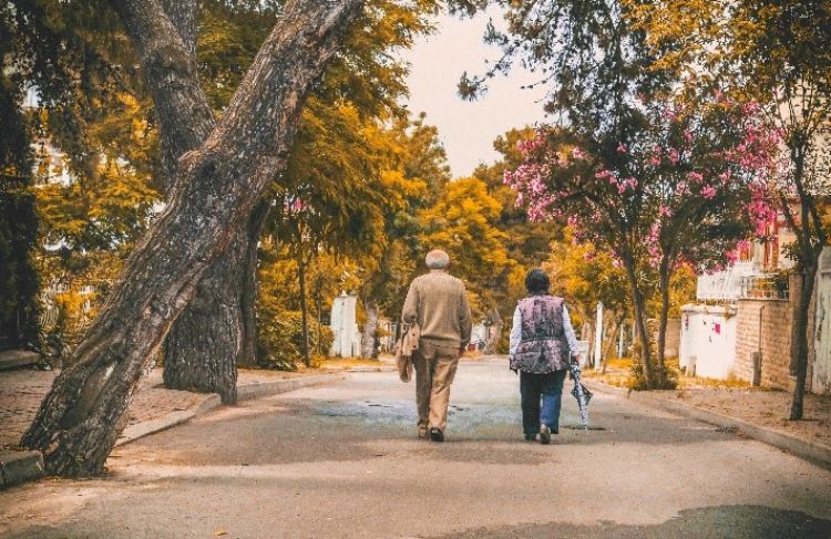 Two people walking down a road on a sunny day.