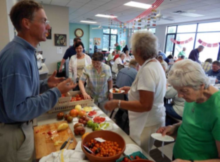 A group of people surrounding a table of food