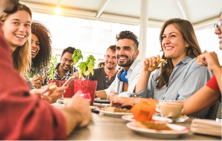 A group of friends talking and eating around a dinner table.