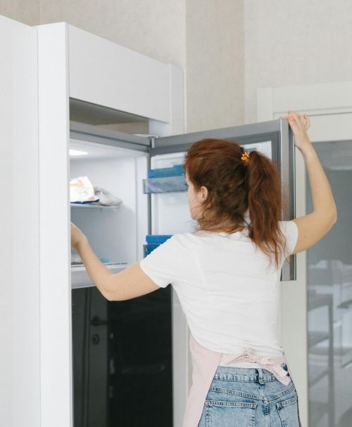 A woman standing in front of her open freezer.