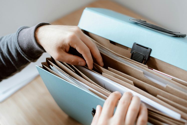 A hand reaching into a file folder.