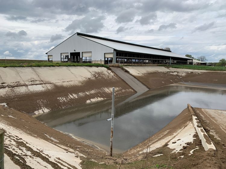 cement manure pit with white barn in background