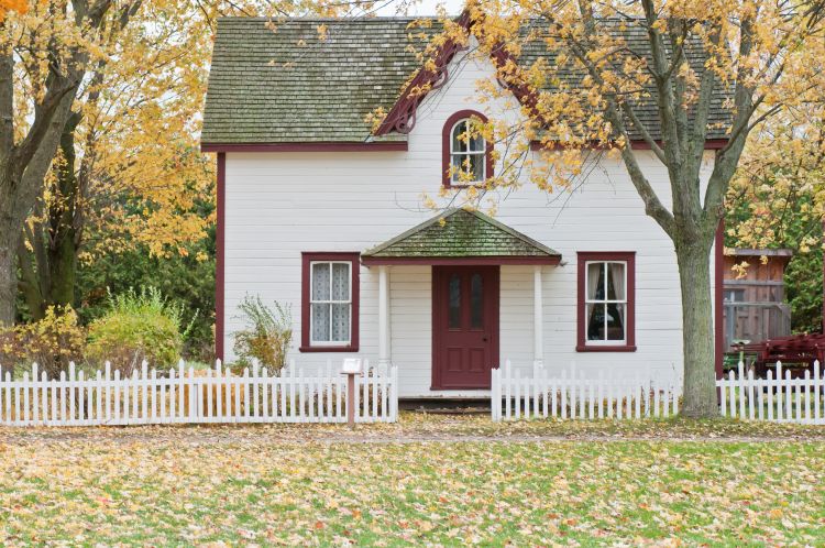 White house with red door and white picket fence out front.