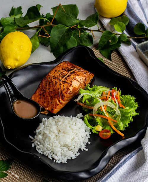 A photo of rice, grilled salmon and salad on a plate.