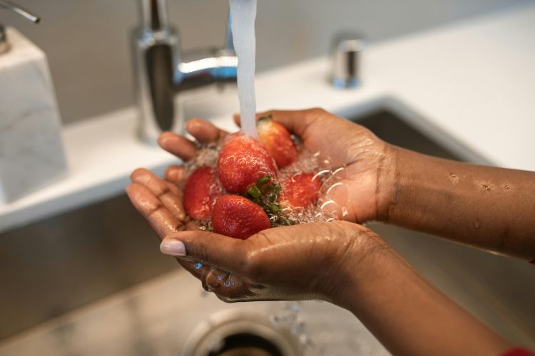 Someone washing strawberries.