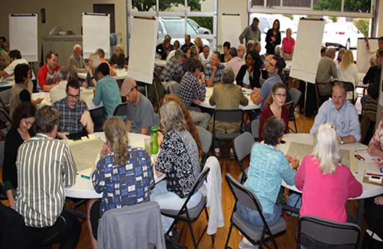 People sitting around tables doing group work during a charrette.