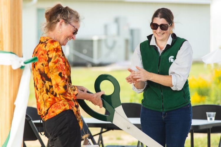 Image of Dr. Meghan Milbrath and Charlotte Hubbard cutting a ceremonial ribbon at the new MSU Pollinator Performance Center Teaching Pavilion.