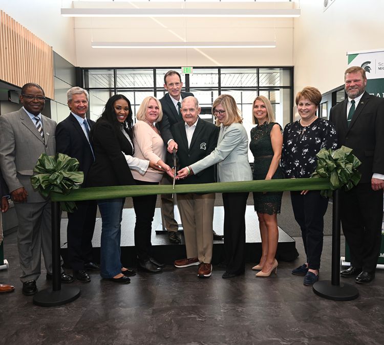 A group of people cut the ribbon to commemorate the newly renovated MSU Packaging Building.
