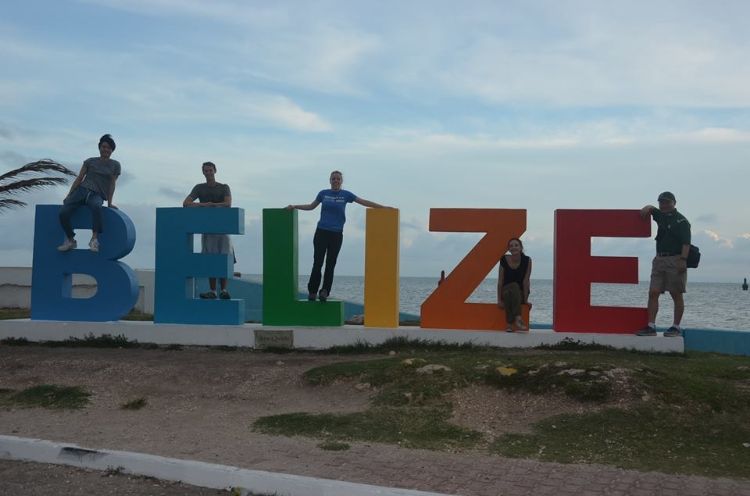 Picture of senior design team next to Belize sign.