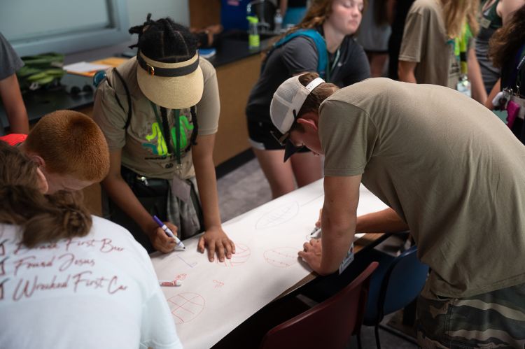 Youth writing on a long piece of paper.