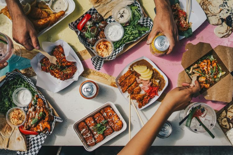 Photo of a meal on a table with multiple hands.