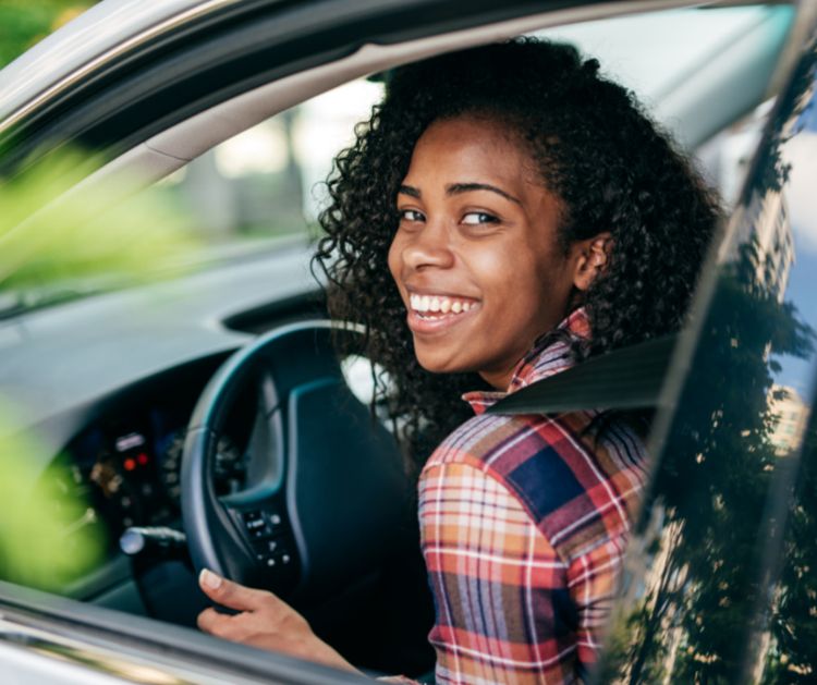 Teen sitting in a car wearing safety belts.