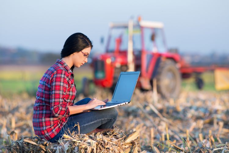 Man standing in field in front of tractor.