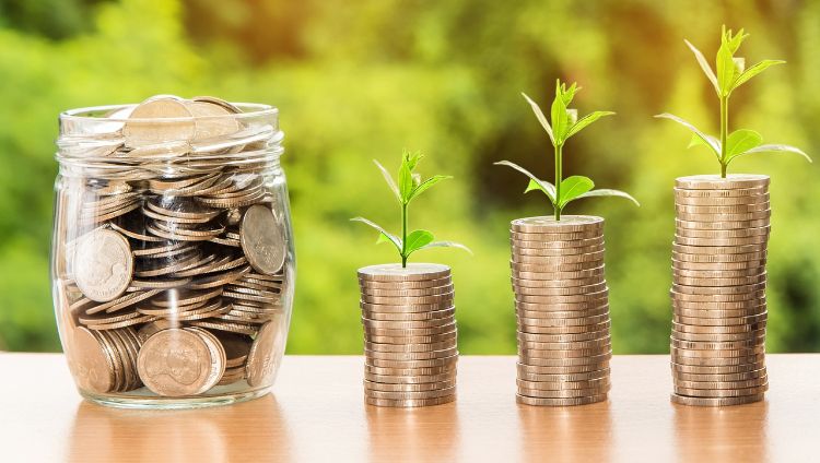 Change in jar as well as stacks of coins with plants growing out of them.