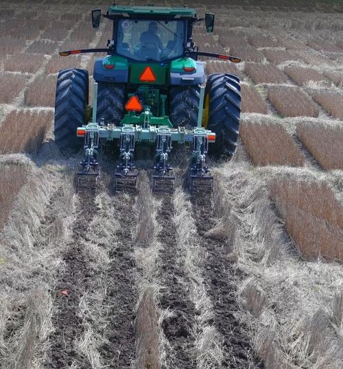 A combine in a wheat field tilling the ground.