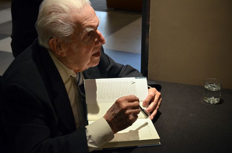 Dr. Howard Tanner sits at a table signing his book for audience members.