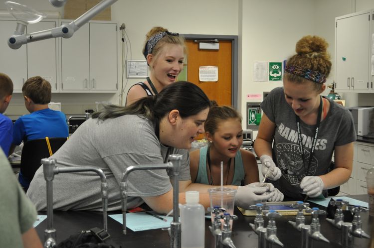 teens working at a science lab wearing gloves.