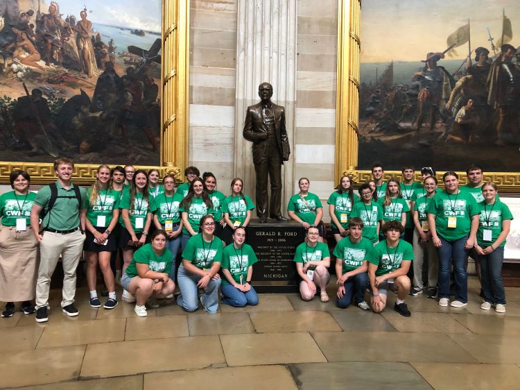 A group of youth in matching green tshirts at a U.S. Capitol memorial.