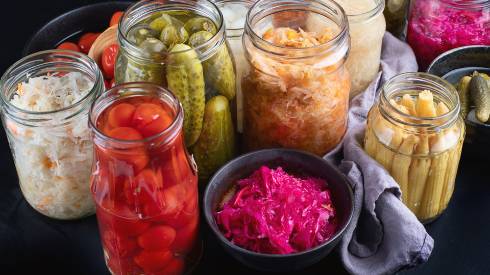 Several jars of fermented foods such as pickles and cabbage.